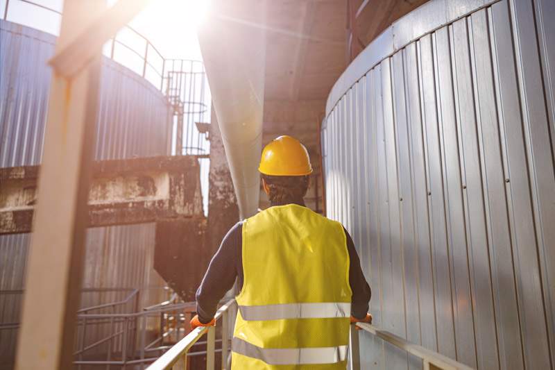 Travailleur masculin debout près d'un conteneur de stockage métallique d'une usine